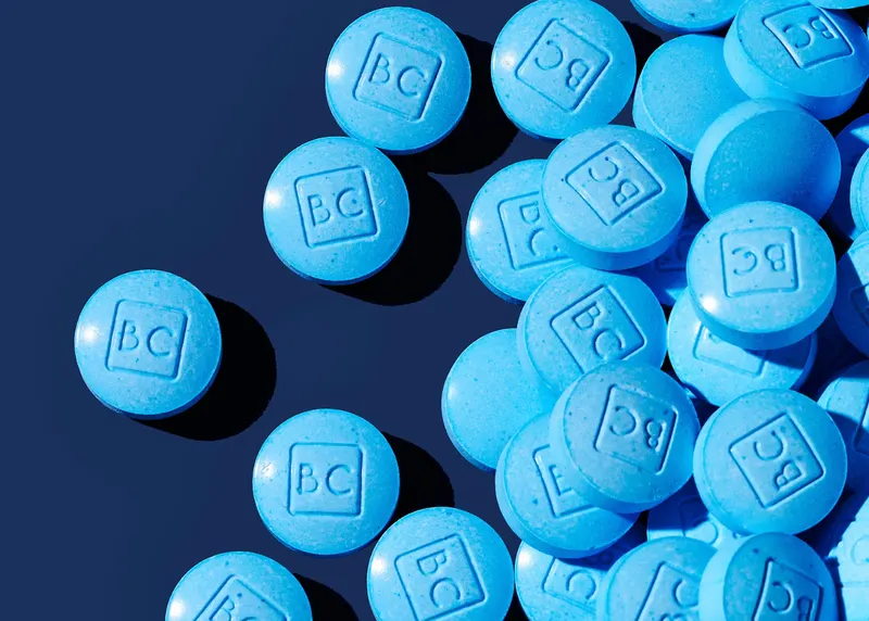 Blue BlueChew tablets with 'BC' imprint on a dark background