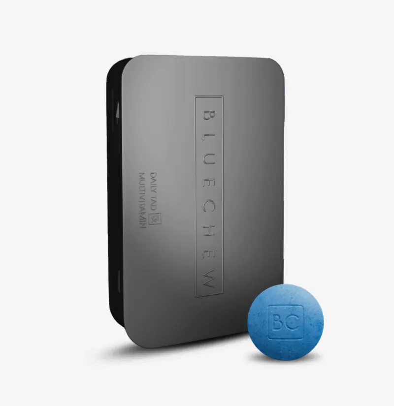 Black BlueChew Daily case with a single blue chewable tablet resting beside it