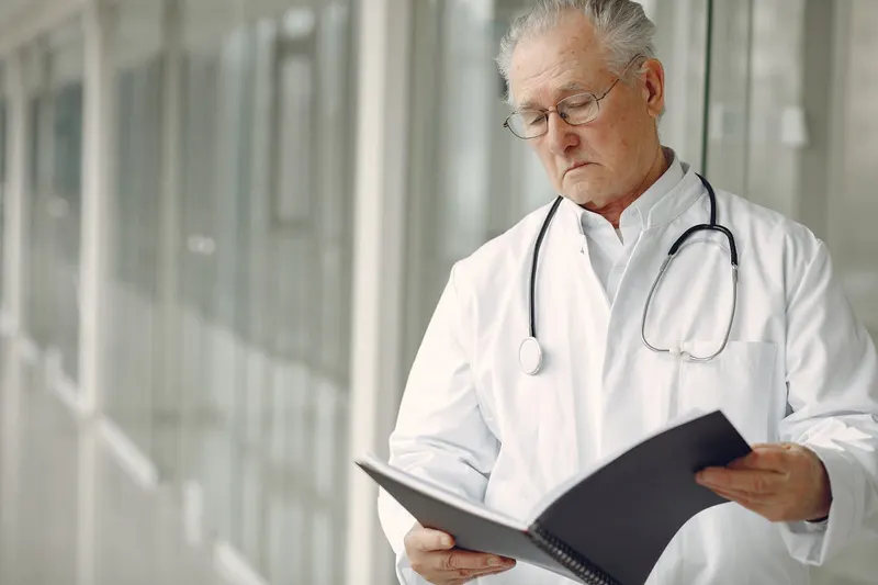 Doctor in a white coat reviewing a notebook in a hospital hallway
