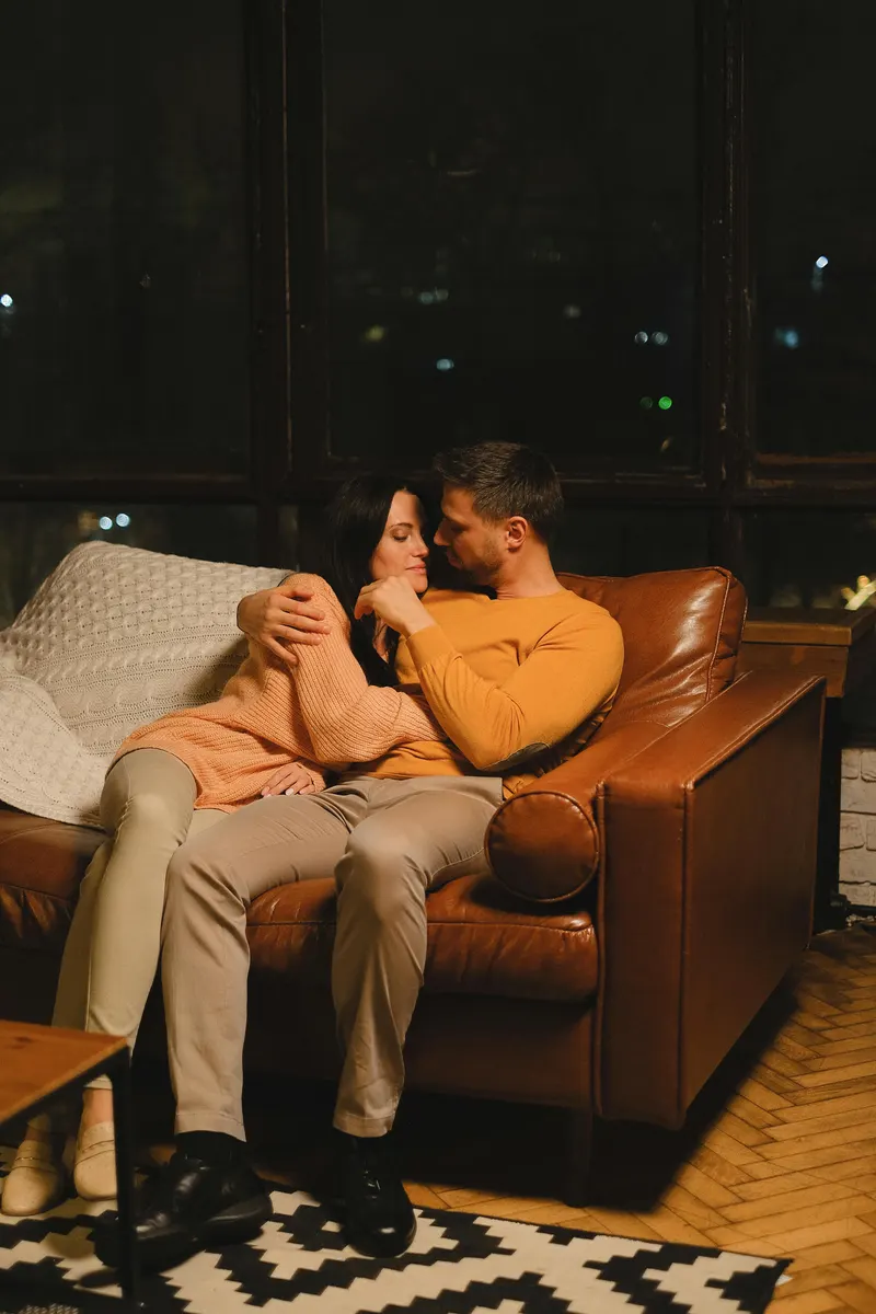 couple cuddling on a brown leather couch 