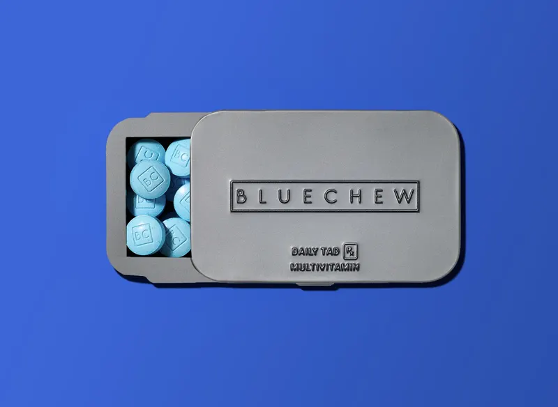 Open gray BlueChew Daily case with blue tablets against a blue background