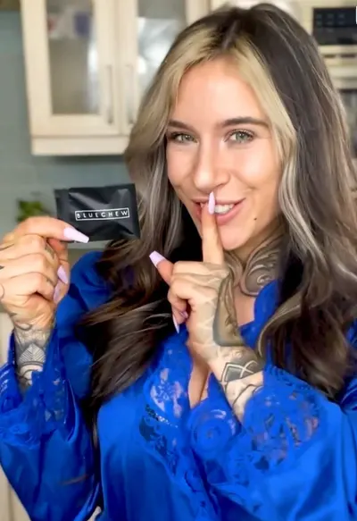 Woman holding a black BlueChew pouch with finger to lips, gesturing discreetly