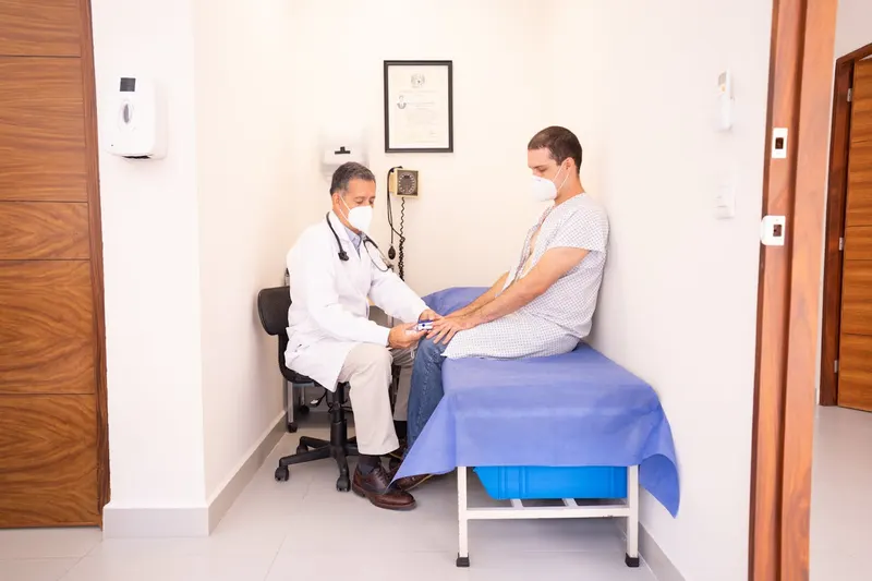 Doctor examining a patient wearing a mask in a medical exam room