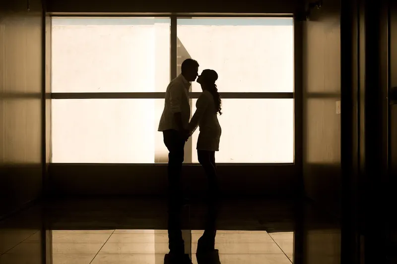 Silhouette of a couple embracing near a bright window"