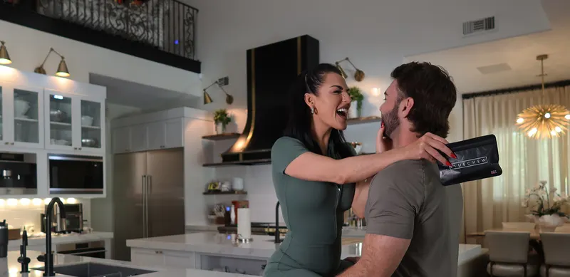 Couple laughing and embracing in a modern kitchen.