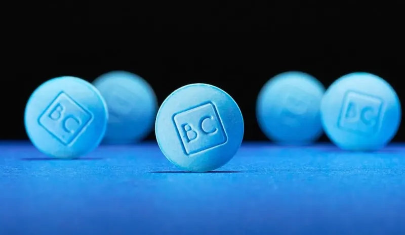 Close-up row of blue BlueChew sublingual tablets on a dark blue surface