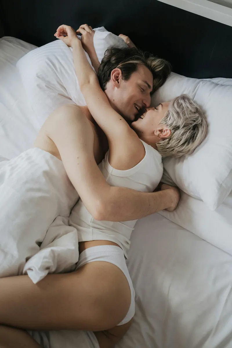 couple in bed snuggling white sheets