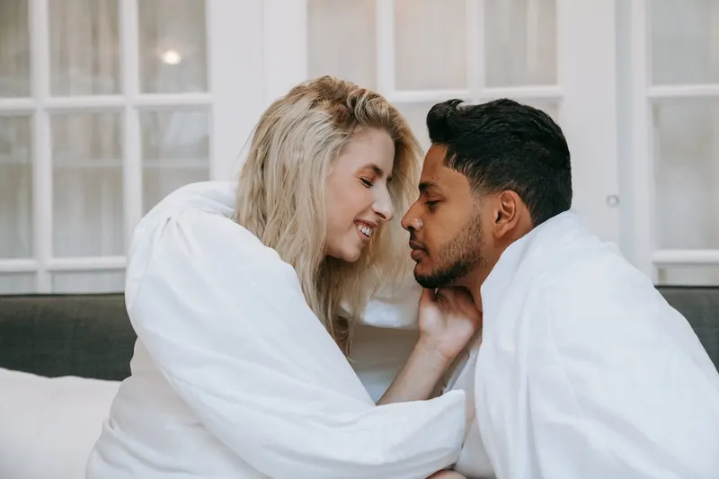 couple wrappeed in the covers face to face smiling