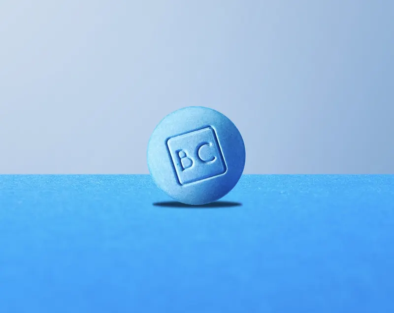single bluechew sublingual tablet with BC imprint on a blue background
