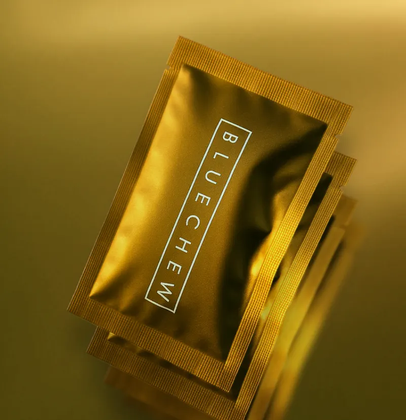 Stack of three BlueChew gold packets on a gold background.