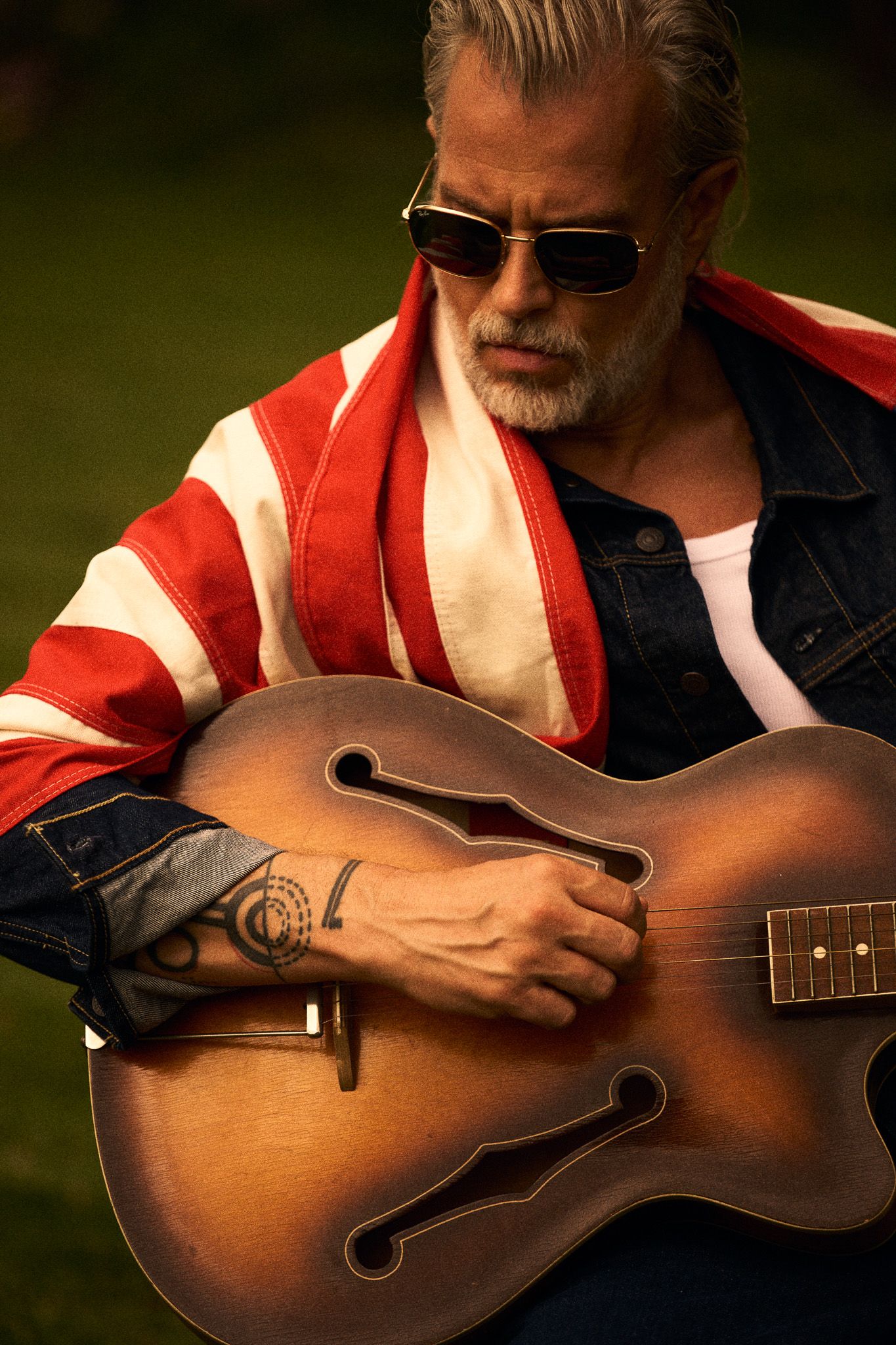 man with US flag tattoos and guitar