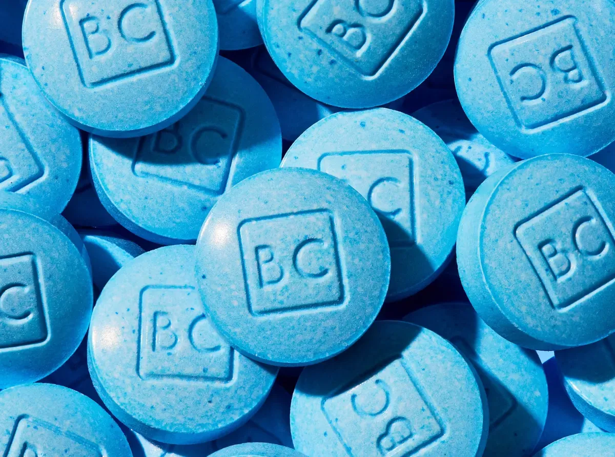 Close-up pile of blue BlueChew chewable tablets stamped with "BC"