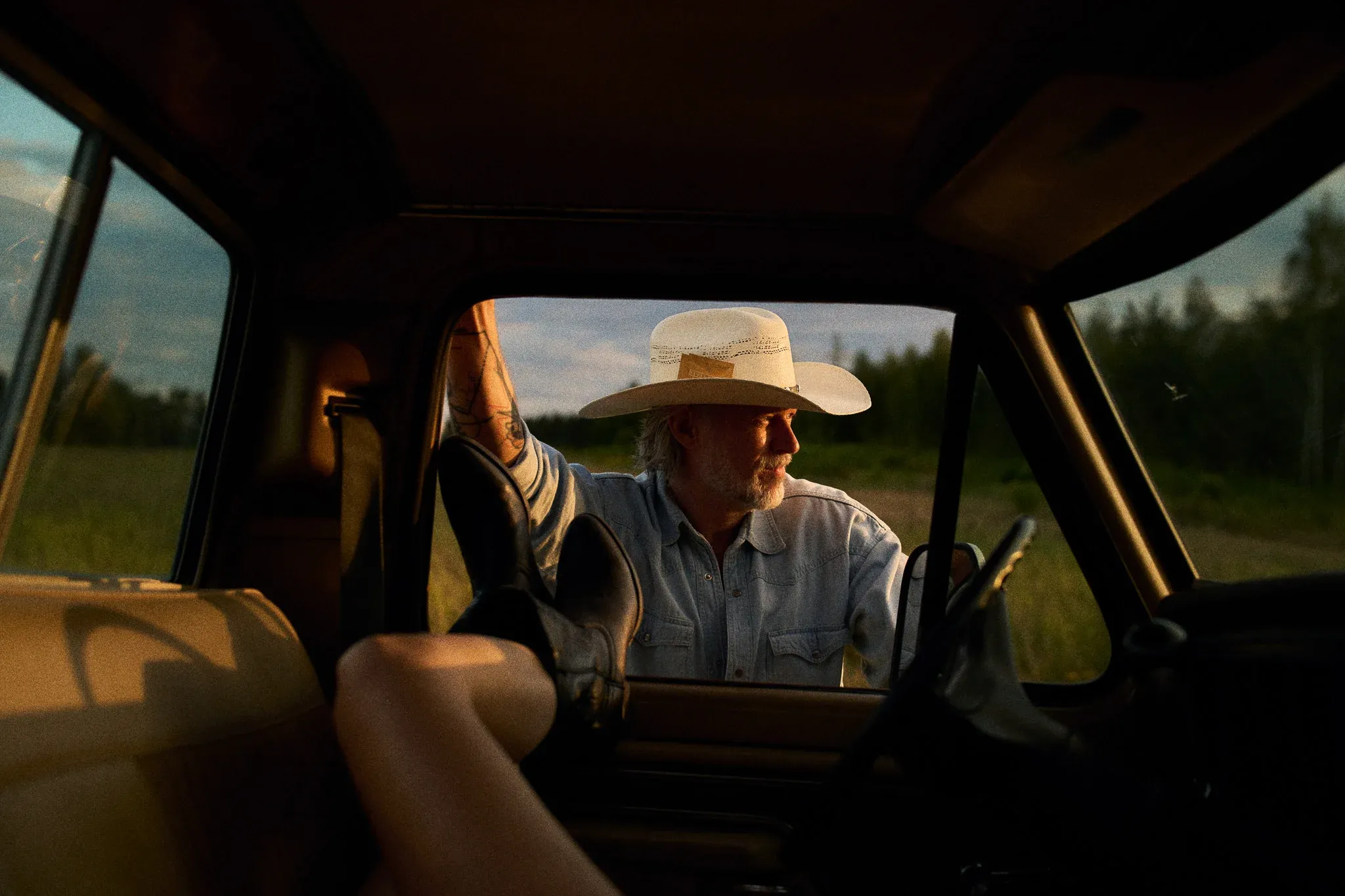 cowboy at pickup truck with womans leg