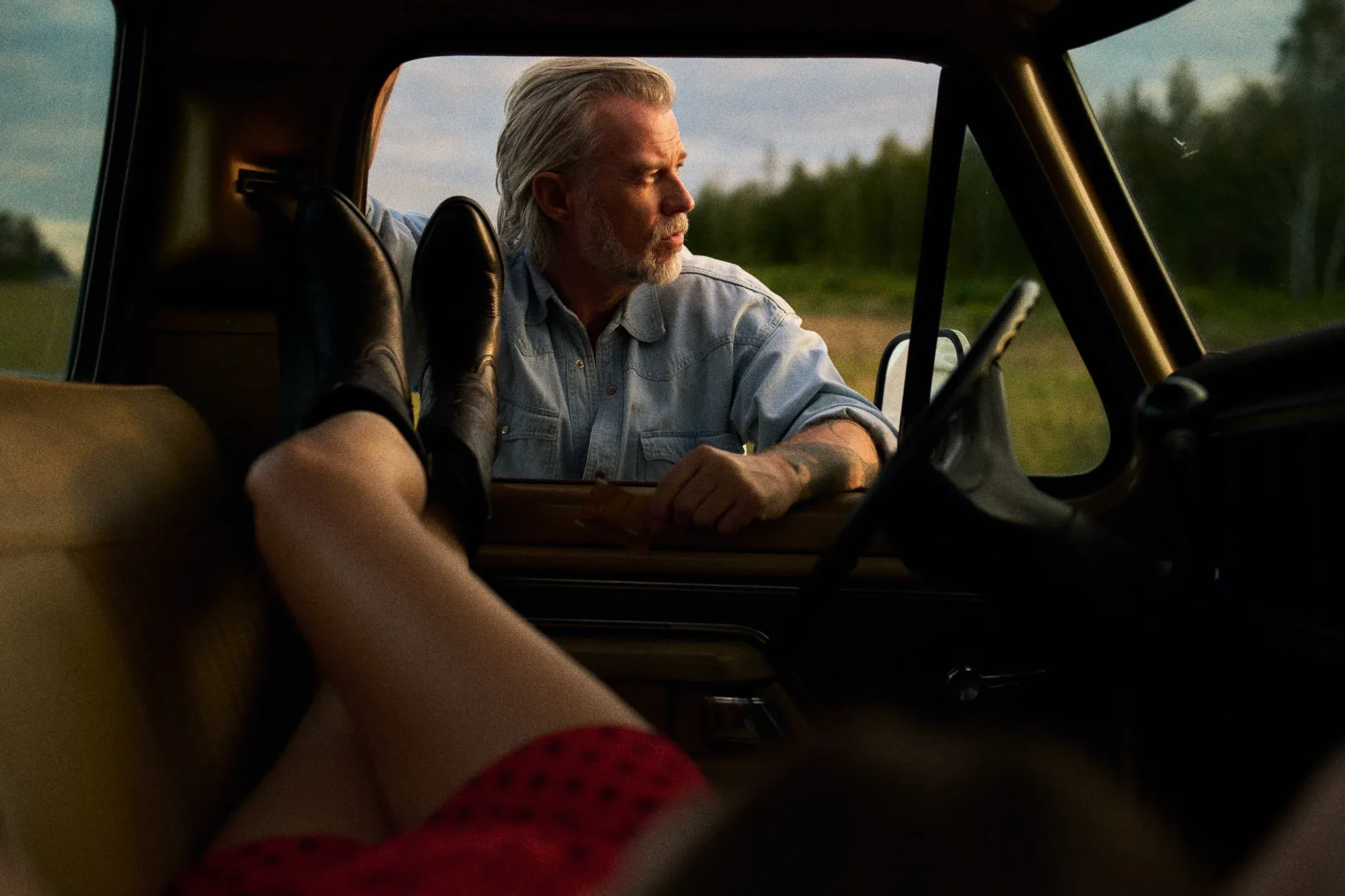 woman in red skirt laying in pickup truck countryside