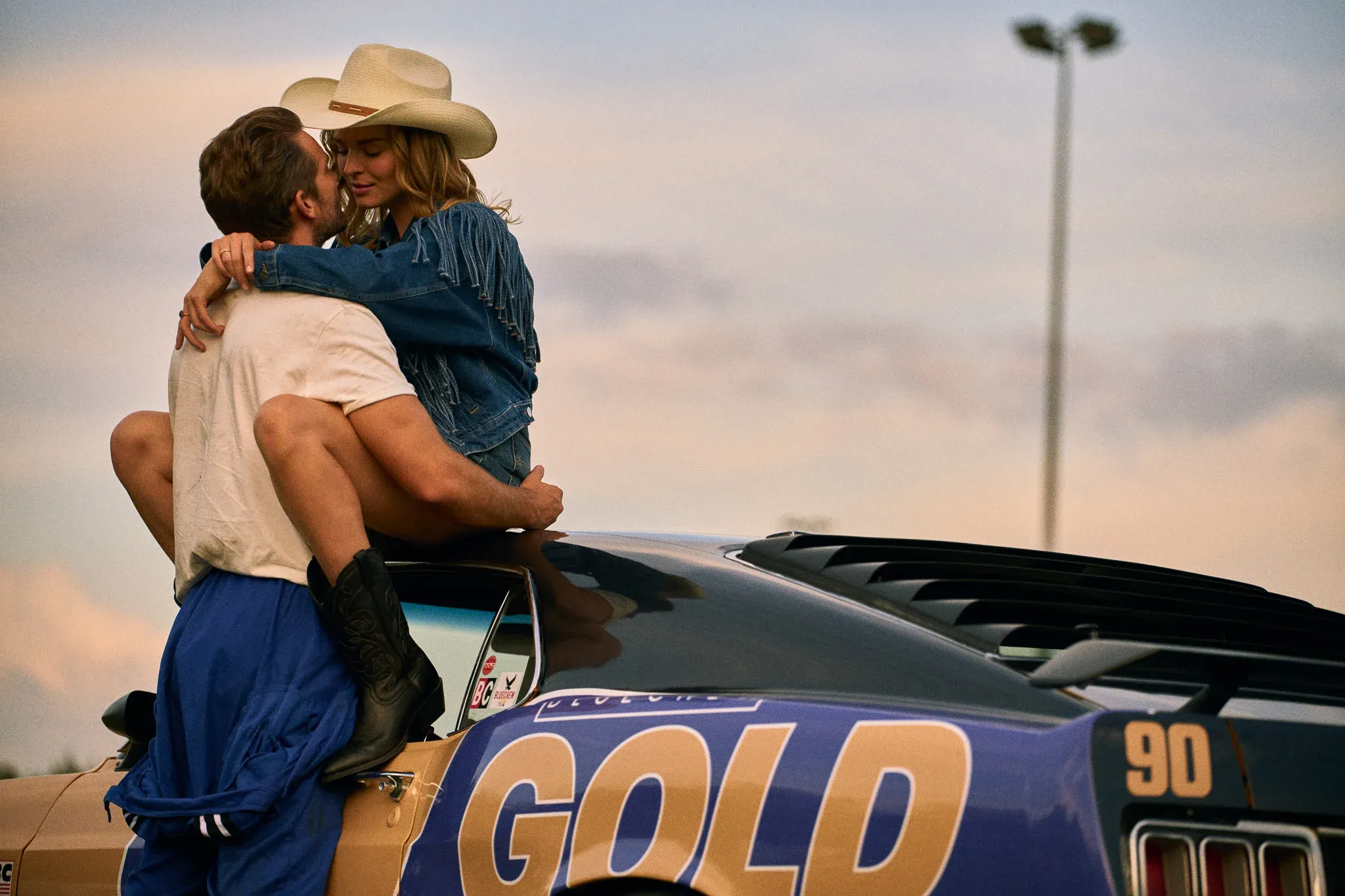 country couple kissing on a race car bluechew gold in hand